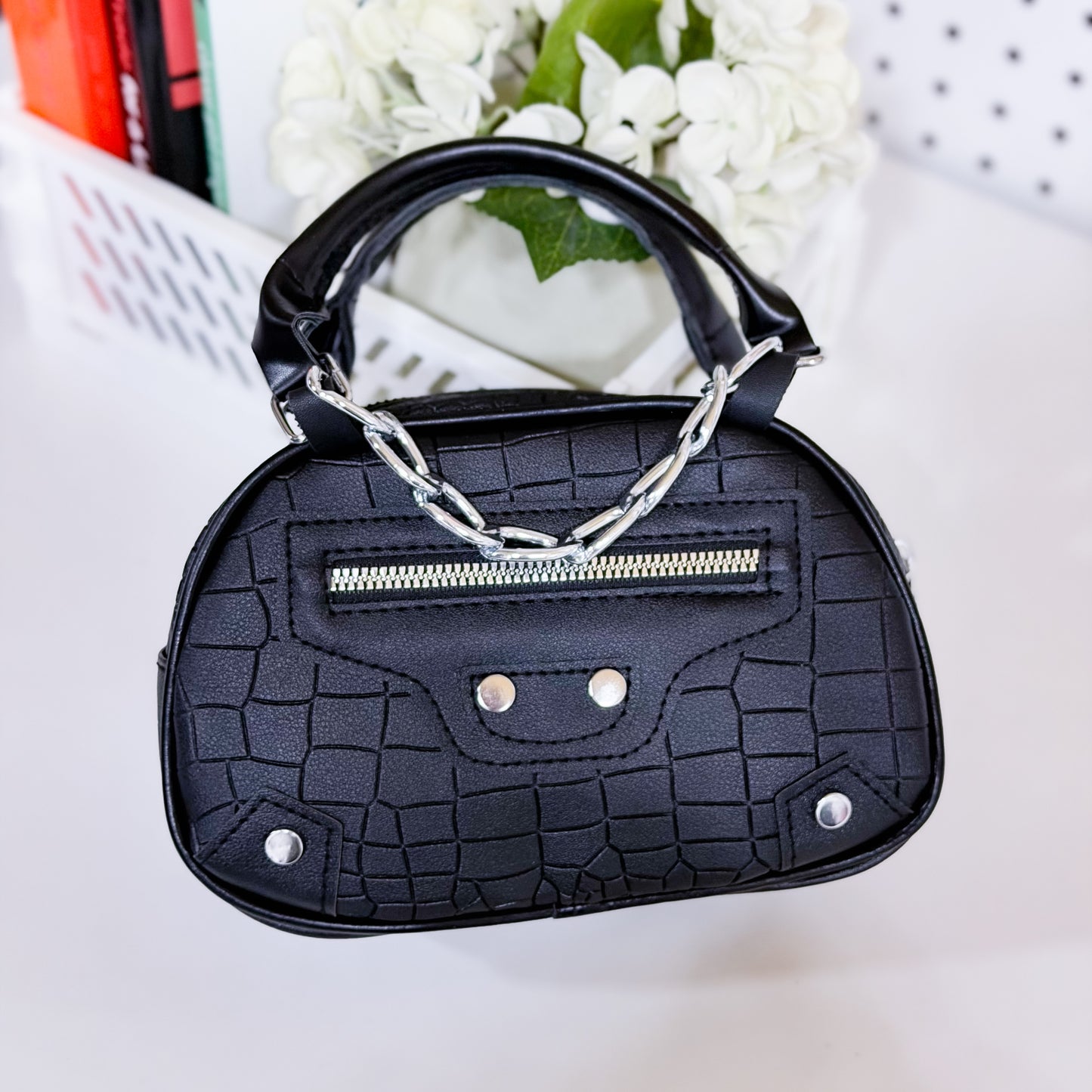 Black textured handbag with silver chain handle on a light background