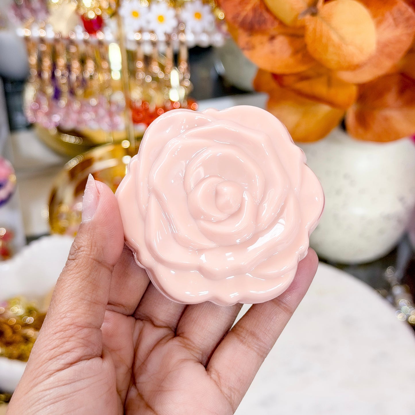 Peach rose compact mirror with a glossy finish, being held in a hand.