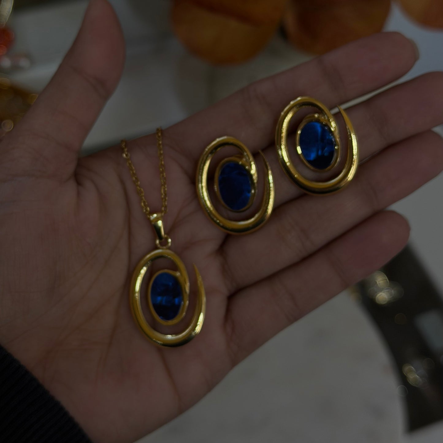 Gold jewelry set with blue stones on a hand