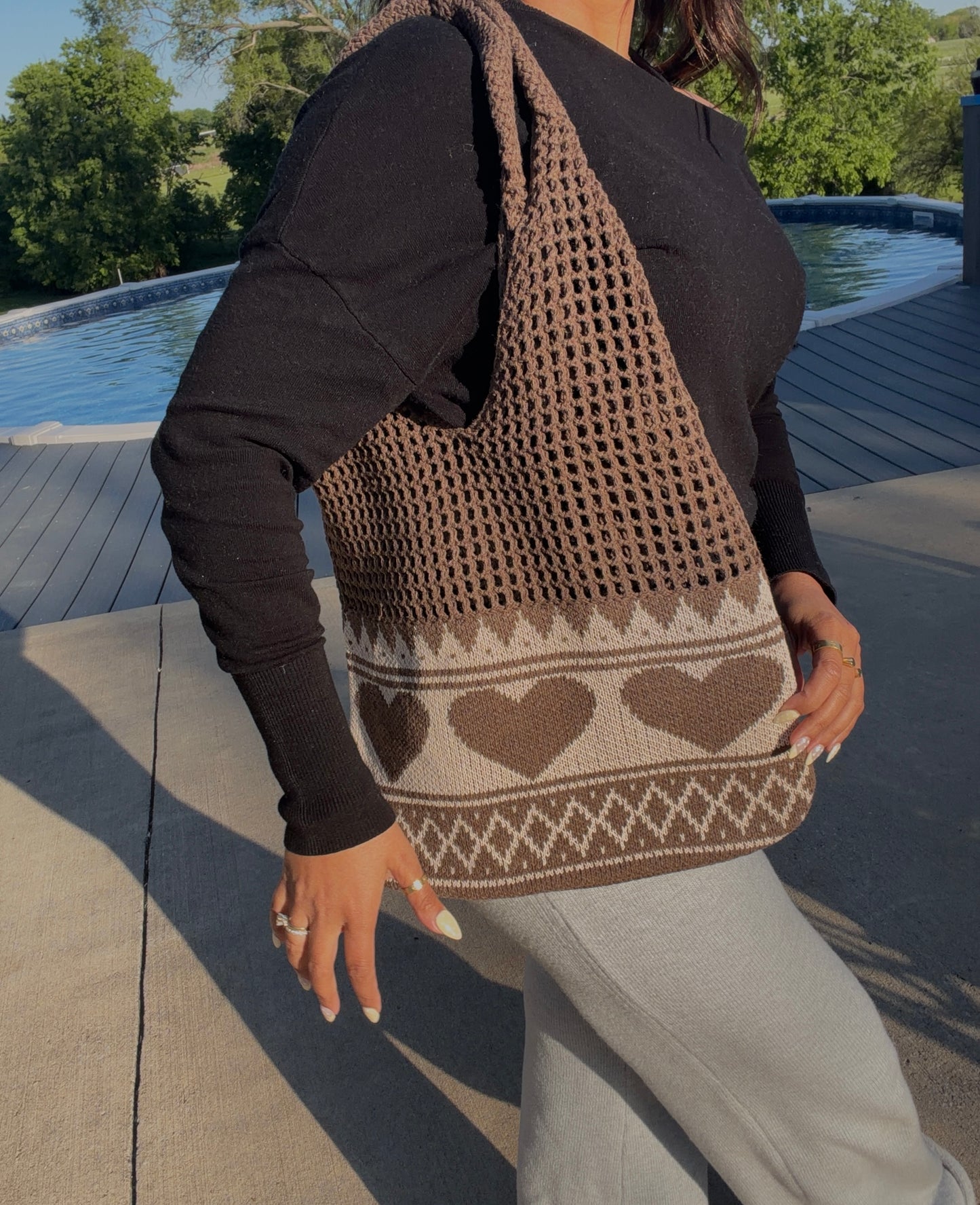 Brown knitted tote bag with a mesh upper and a cream lower section featuring brown hearts and geometric motifs.
