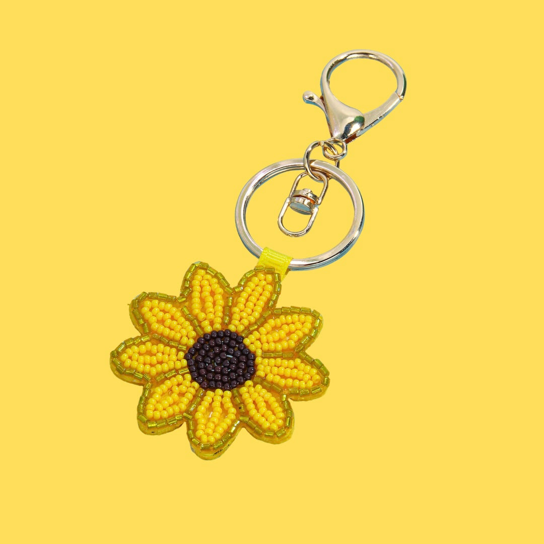Yellow beaded sunflower bag charm with a dark brown center, attached to a silver-tone metal keyring and clasp.