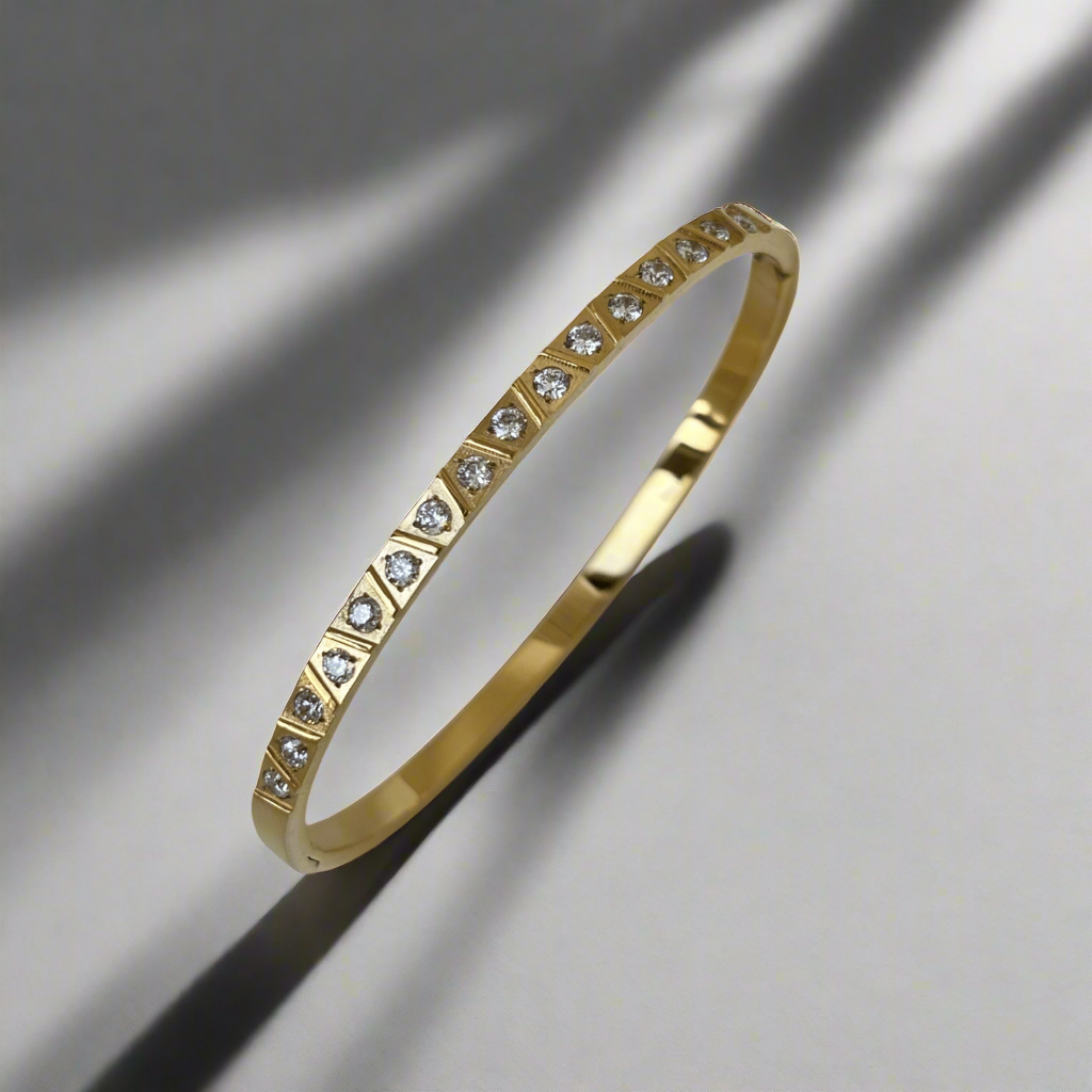 Gold bangle bracelet by Miansai with diamond accents and triangular shapes.