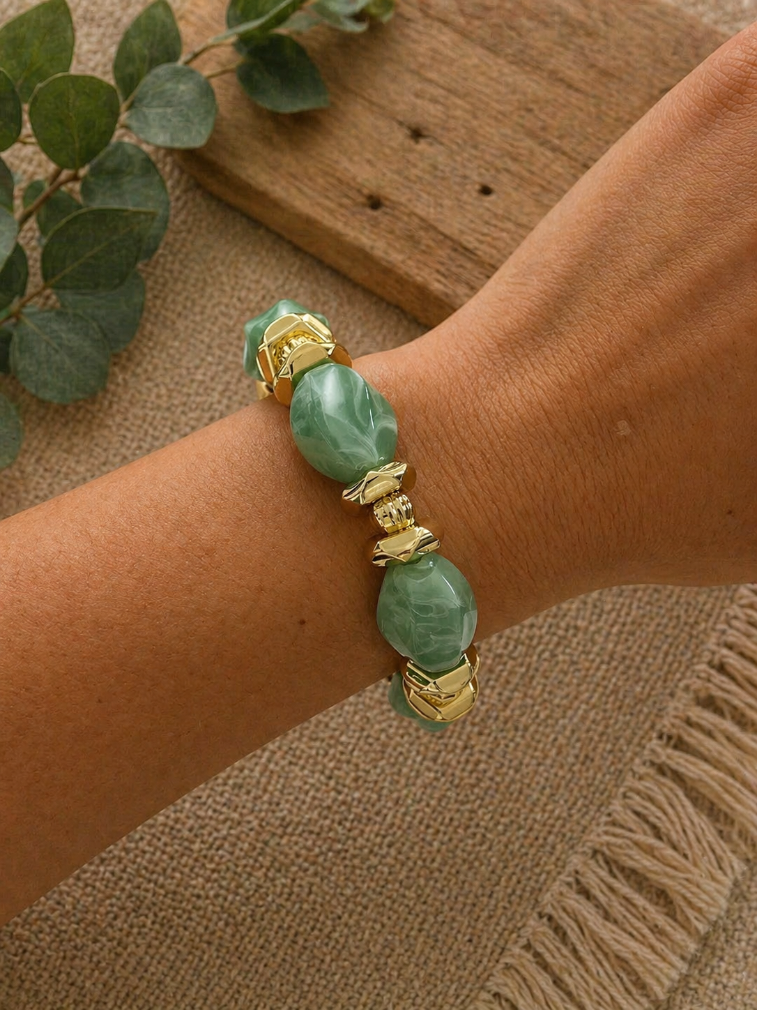 Coastal Sage bracelet with irregular sage green swirled beads and ornate gold accents, worn on a wrist.