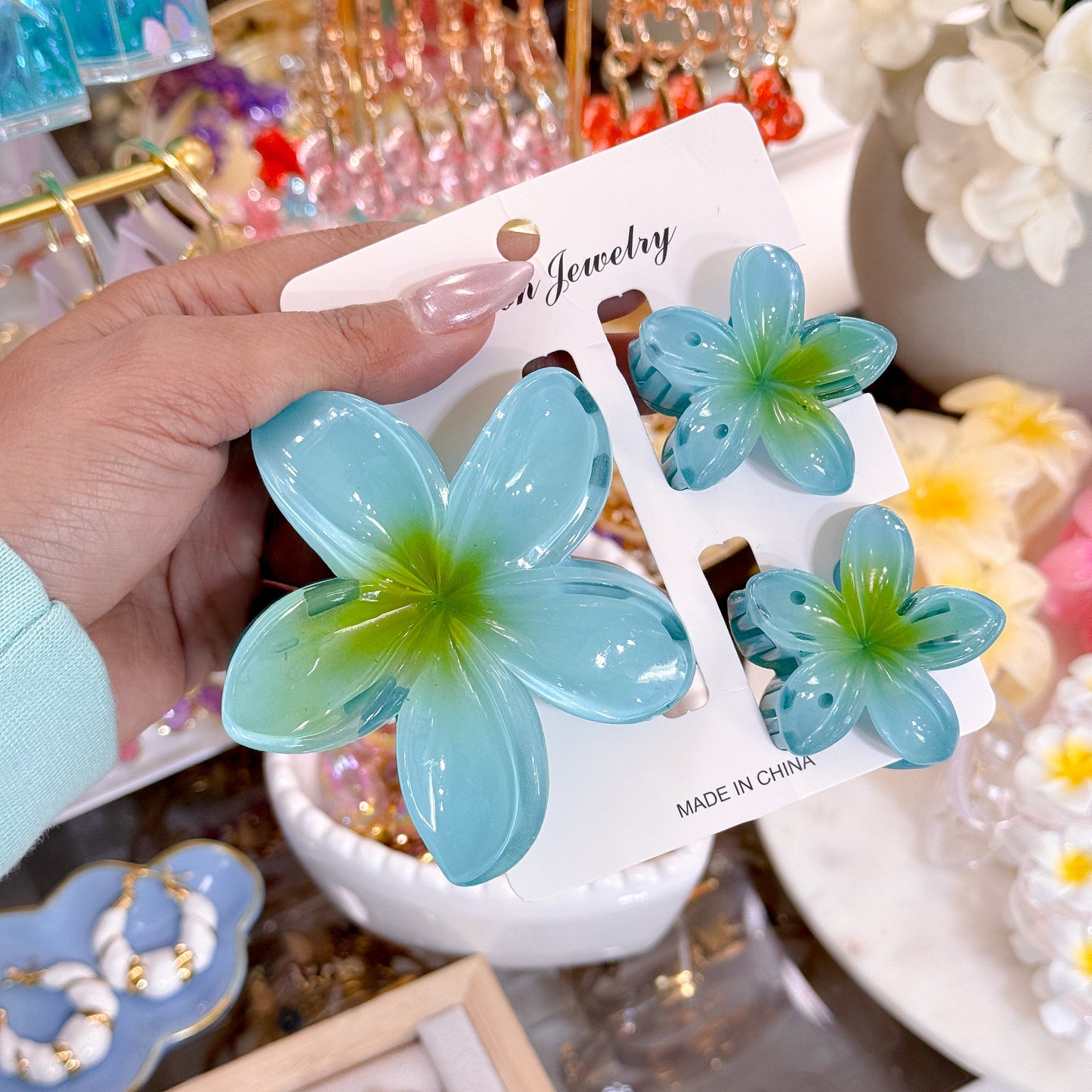 Blue plumeria hair clip sets by Fashion Jewelry, featuring a translucent aqua finish and a green center.