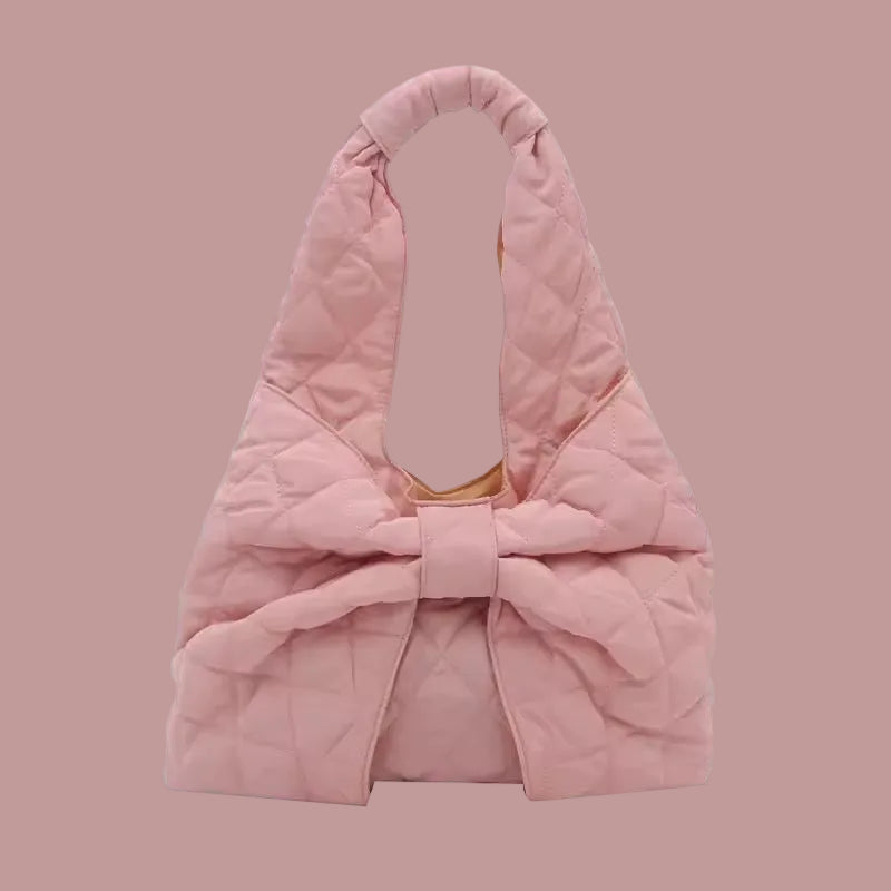 Pink shoulder bag with a large decorative bow detail on the front, featuring a soft, puffy texture.