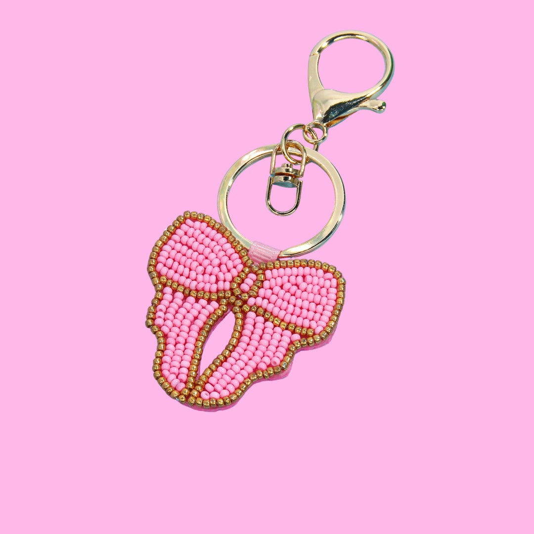 Pink and gold beaded bow bag charm with attached gold keychain clip and ring.