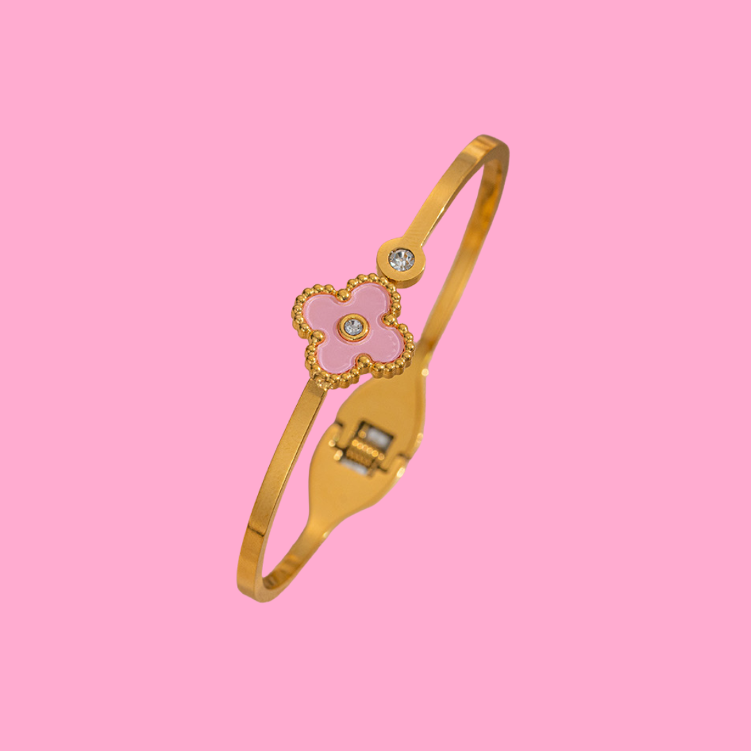 Gold bangle by Starlit, featuring a pink four-leaf clover with sparkling gemstone accents.