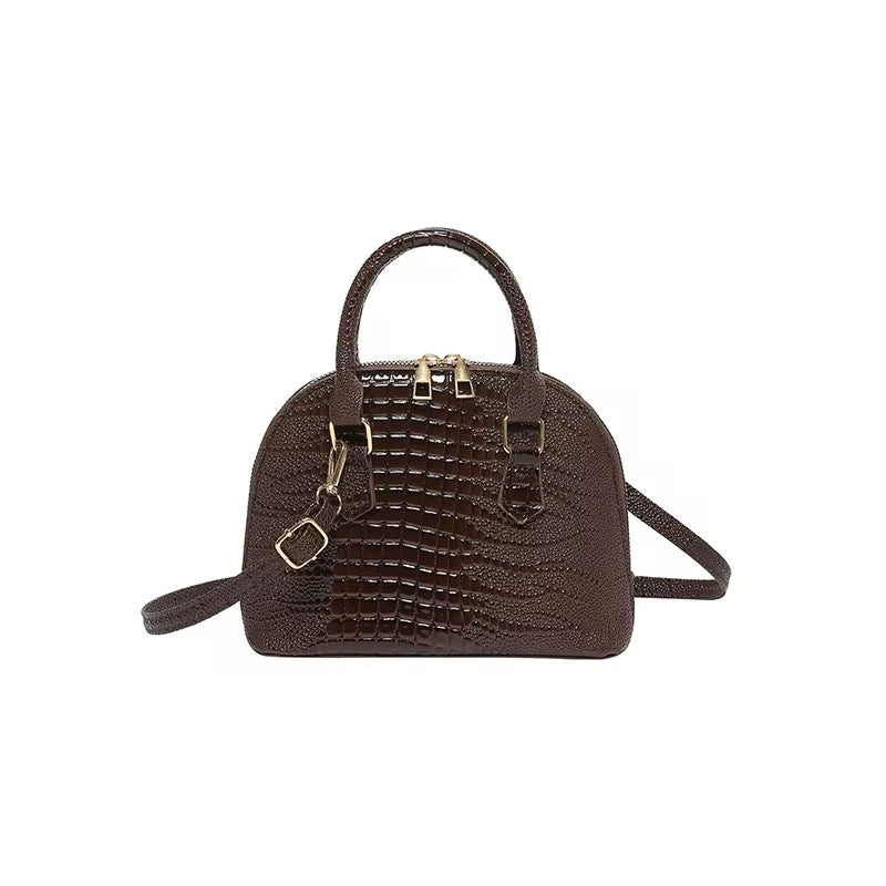 Brown dome crossbody bag with a faux crocodile pattern.