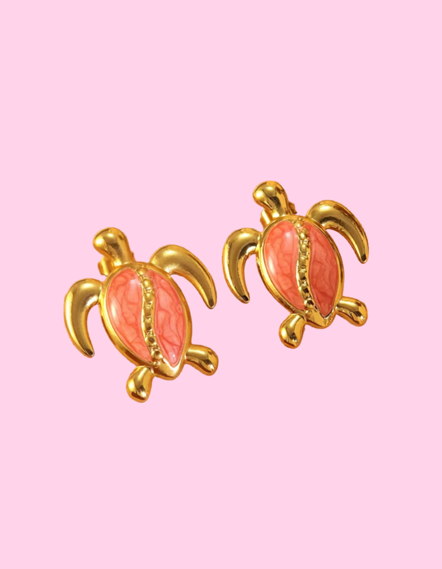 Two gold-toned turtle stud earrings with marbled pink shells, displayed on a soft pink background.