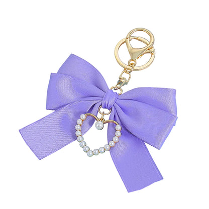 Purple Coquette Pearl Bag Charm with a large satin bow, pearl-adorned heart charm, and gold-toned keyring.