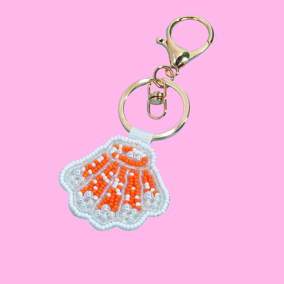 Orange shell beaded bag charm with white and orange seed beads, small pearls, and gold-tone hardware.