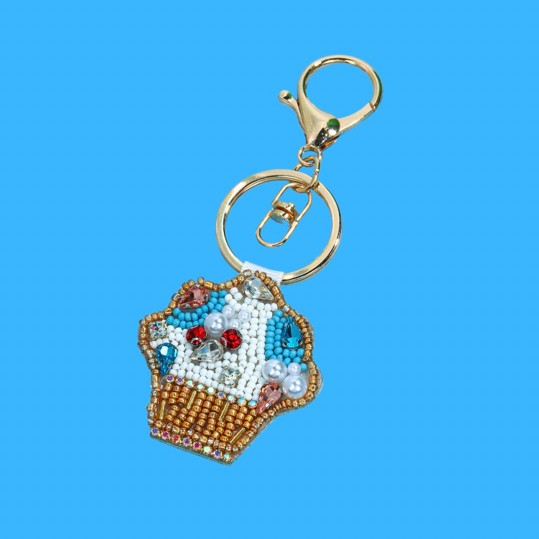 A colorful beaded cupcake bag charm with gold keyring, featuring blue, white, gold, pink, and red beads with clear gems.