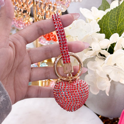 Red rhinestone heart keychain with wrist strap and gold-tone key ring, shown held in hand.