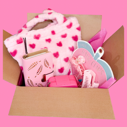 Pink Valentine gift set displayed in an open cardboard box showing a plush pink heart tote, pink wallet, jewelry box, and hair clip set.
