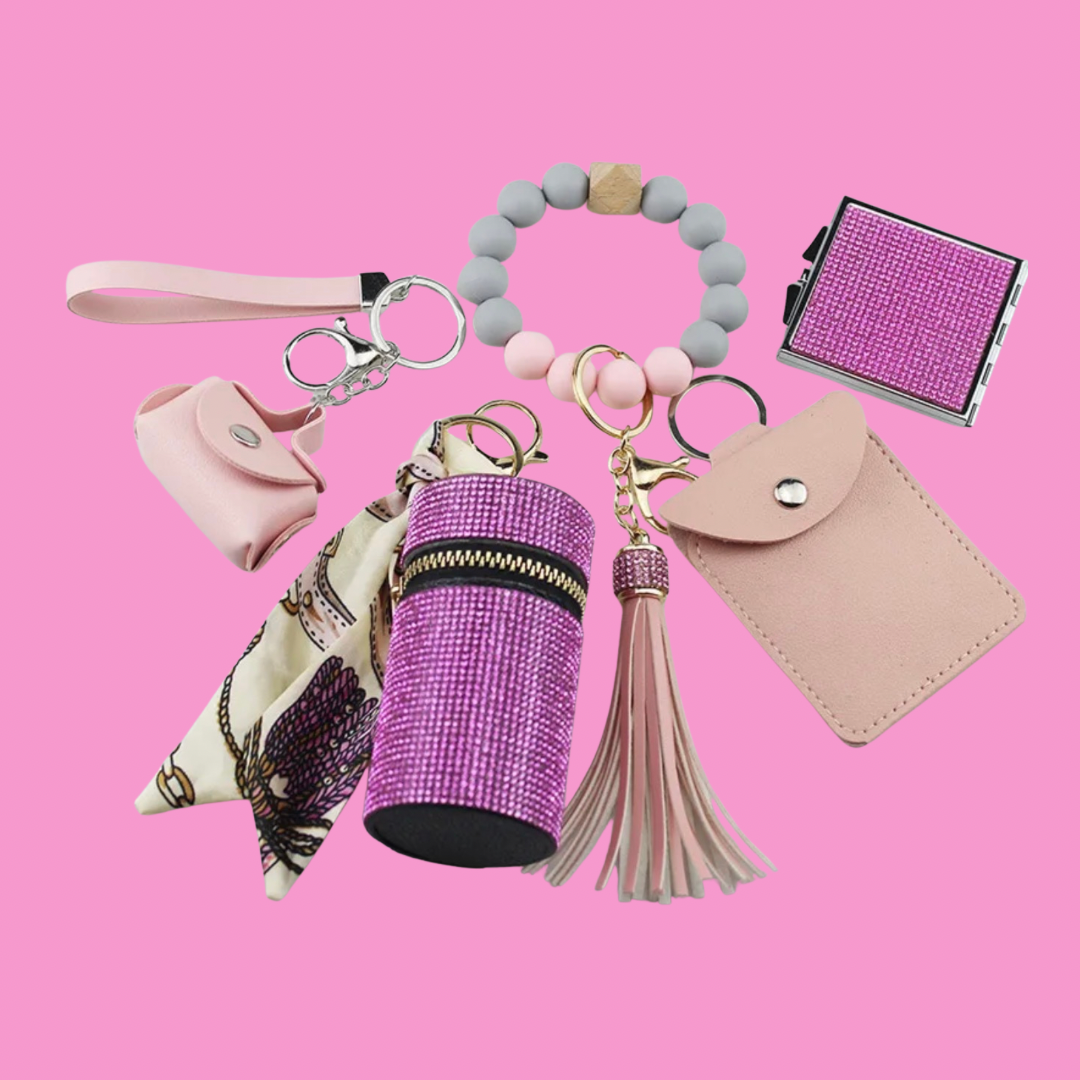 Pink Luxe keychain wristlet accessory set featuring a beaded wristlet, rhinestone zip pouch, mini pouch, tassel charm, card holder, and sparkly compact mirror in coordinating colors.