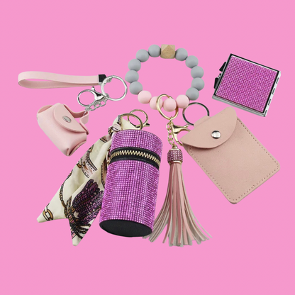 Pink Luxe keychain wristlet accessory set featuring a beaded wristlet, rhinestone zip pouch, mini pouch, tassel charm, card holder, and sparkly compact mirror in coordinating colors.