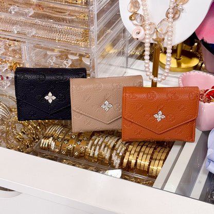 Small leather wallet by Belle with textured floral pattern and rhinestone flower accent.