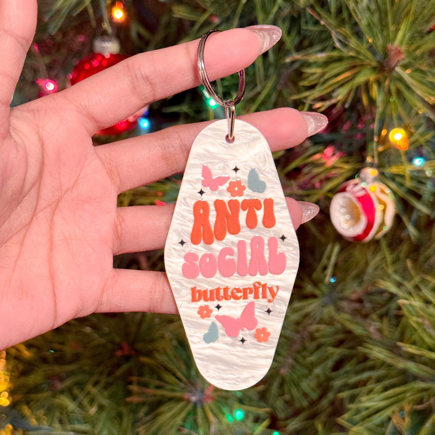 White retro motel keychain with "Anti Social Butterfly" graphic print, plus butterflies and flowers.