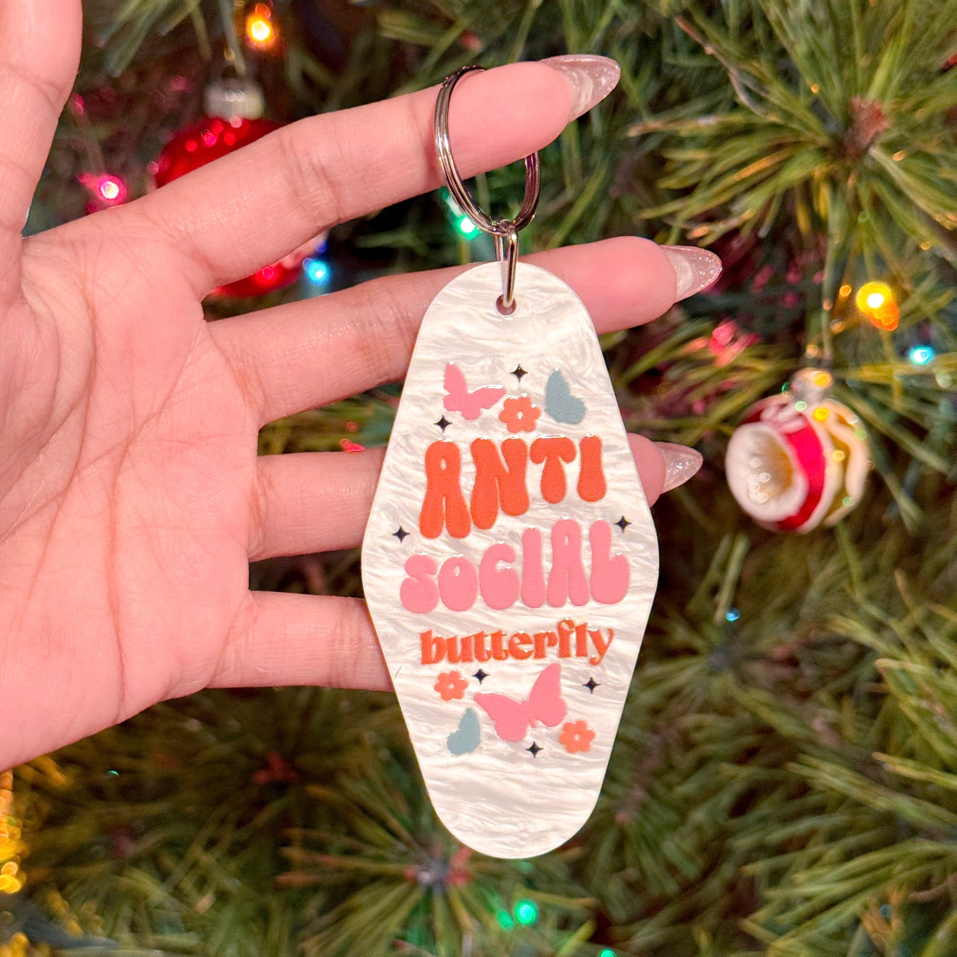 White retro motel keychain with "Anti Social Butterfly" graphic print, plus butterflies and flowers.