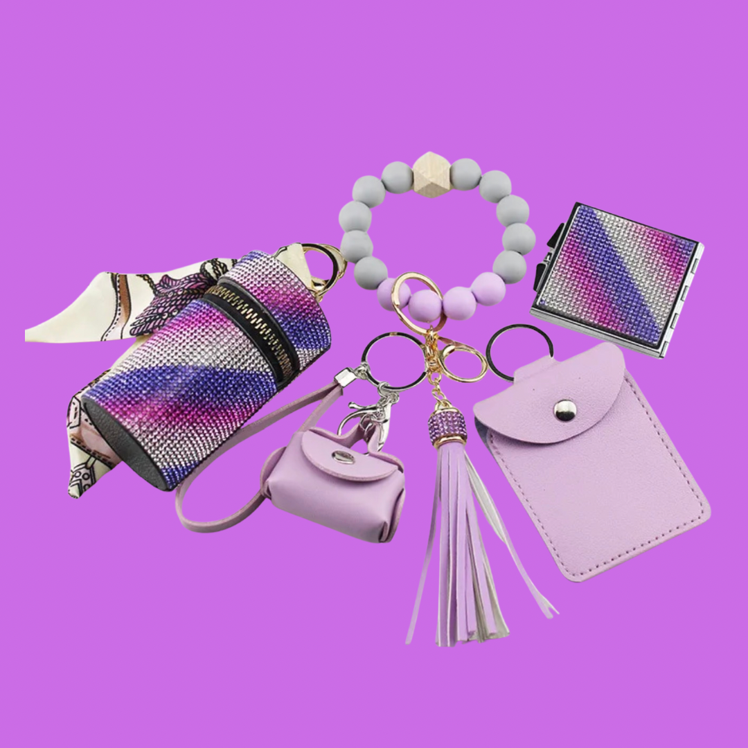 Purple Luxe keychain wristlet accessory set featuring a beaded wristlet, rhinestone zip pouch, mini pouch, tassel charm, card holder, and sparkly compact mirror in coordinating colors.