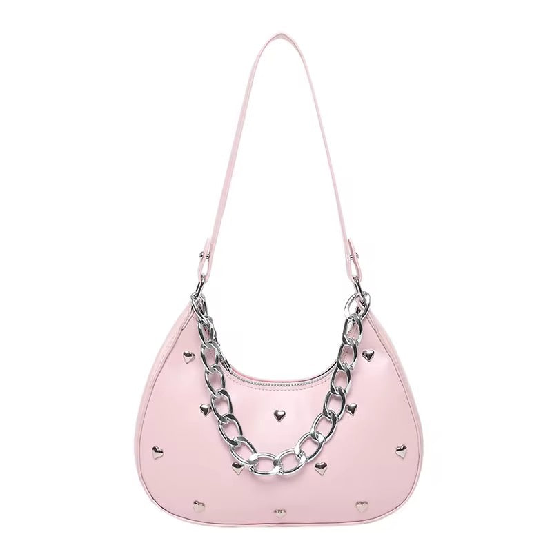 Pink handbag with silver chain detail and heart accents, displayed on a white background.