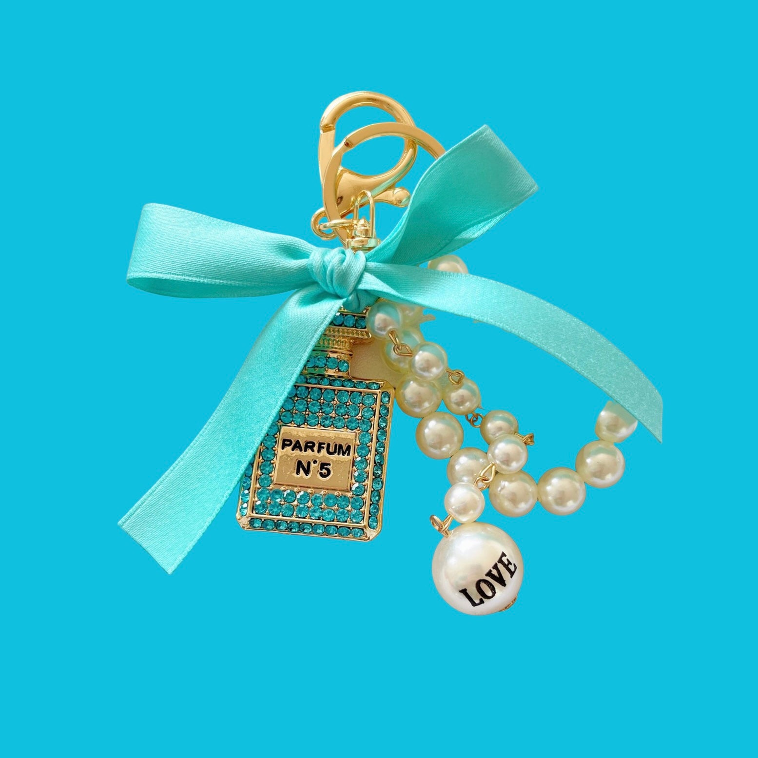 Pearl parfum shape bag charm with crystals, by a vendor, featuring a blue ribbon bow and faux pearl strand.