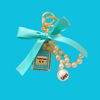 Pearl parfum shape bag charm with crystals, by a vendor, featuring a blue ribbon bow and faux pearl strand.