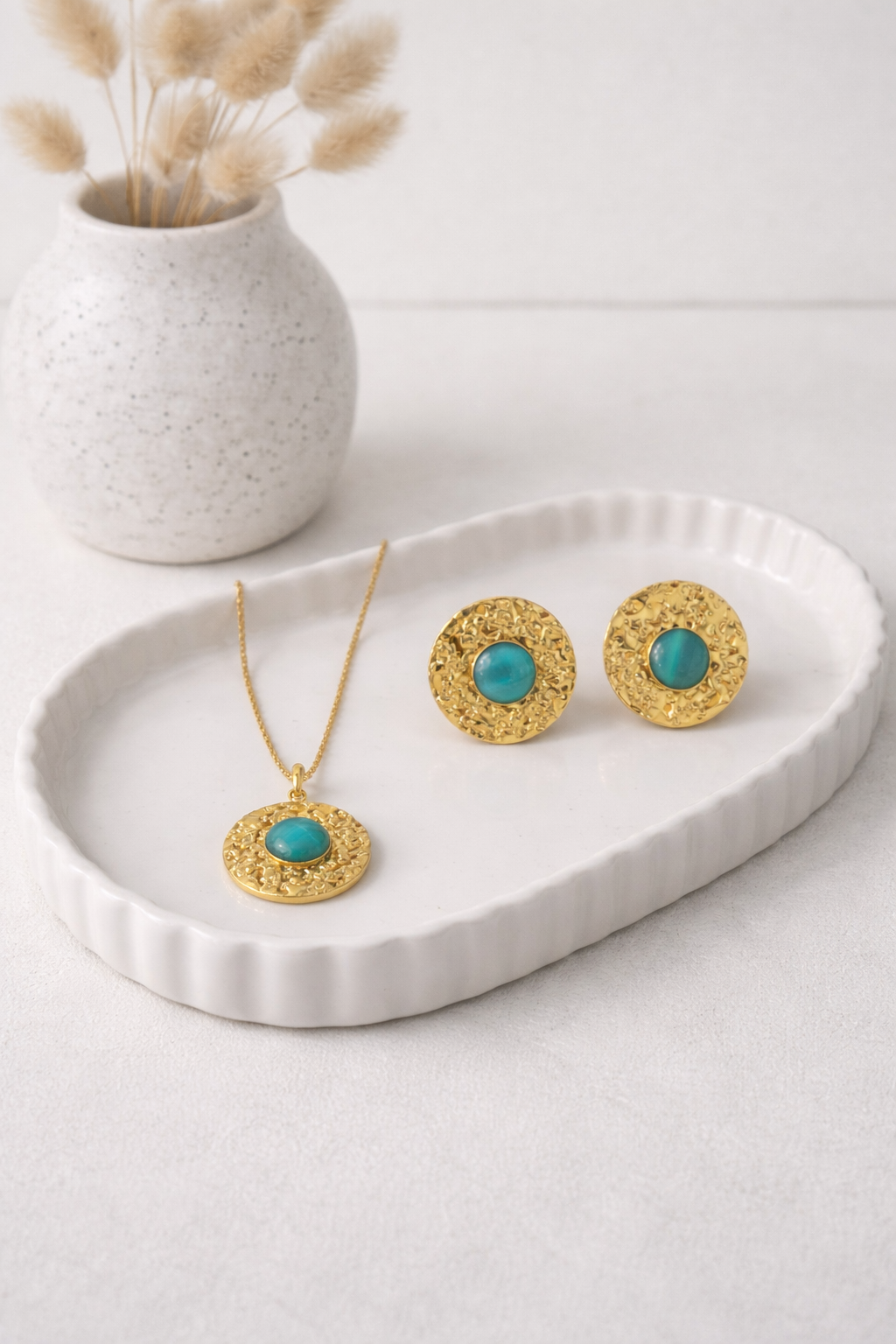 Gold-tone hammered metal Turquoise Medallion Necklace and Earrings Set on a white ribbed tray.