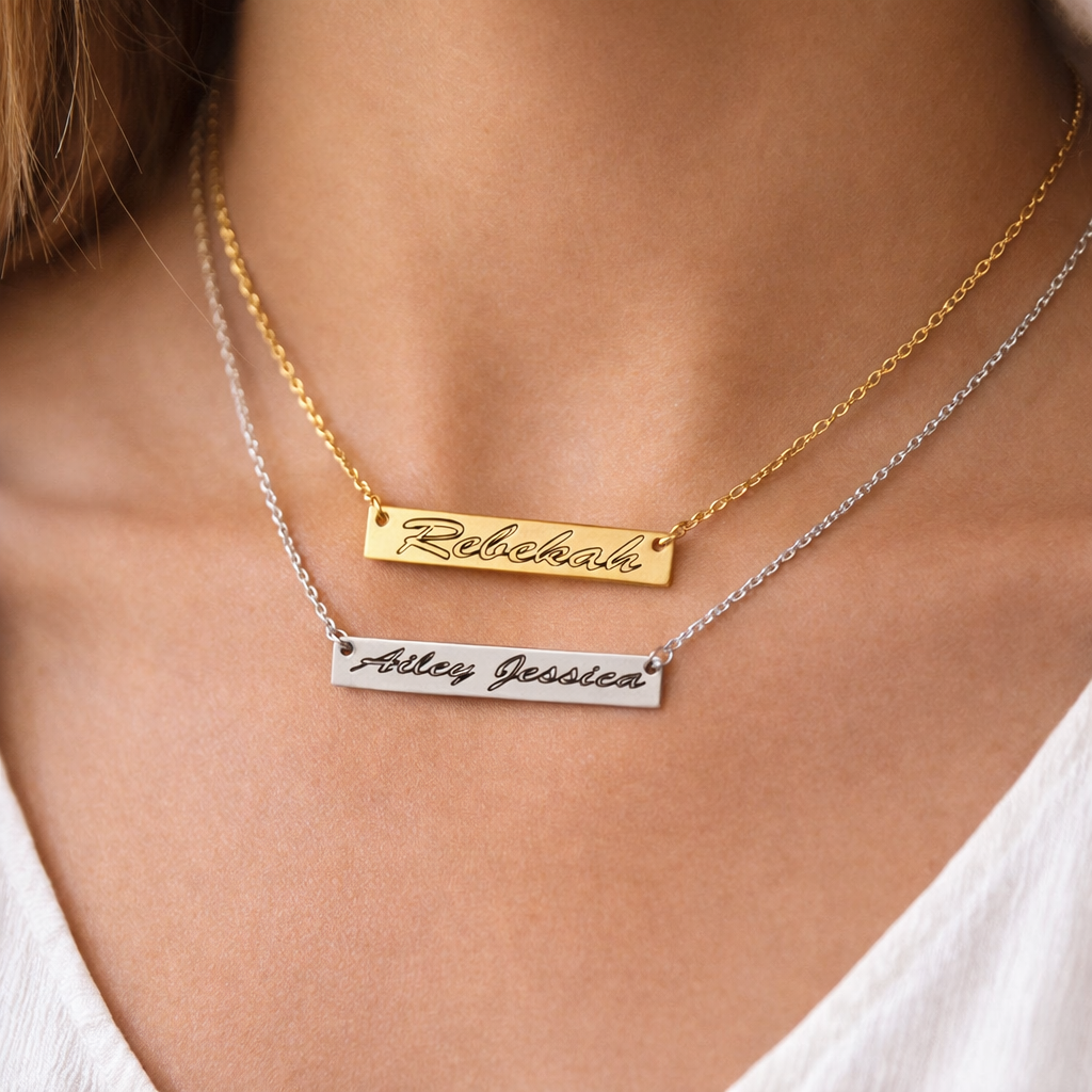 Personalized bar necklace with engraved names by custom design, layered with a second necklace.
