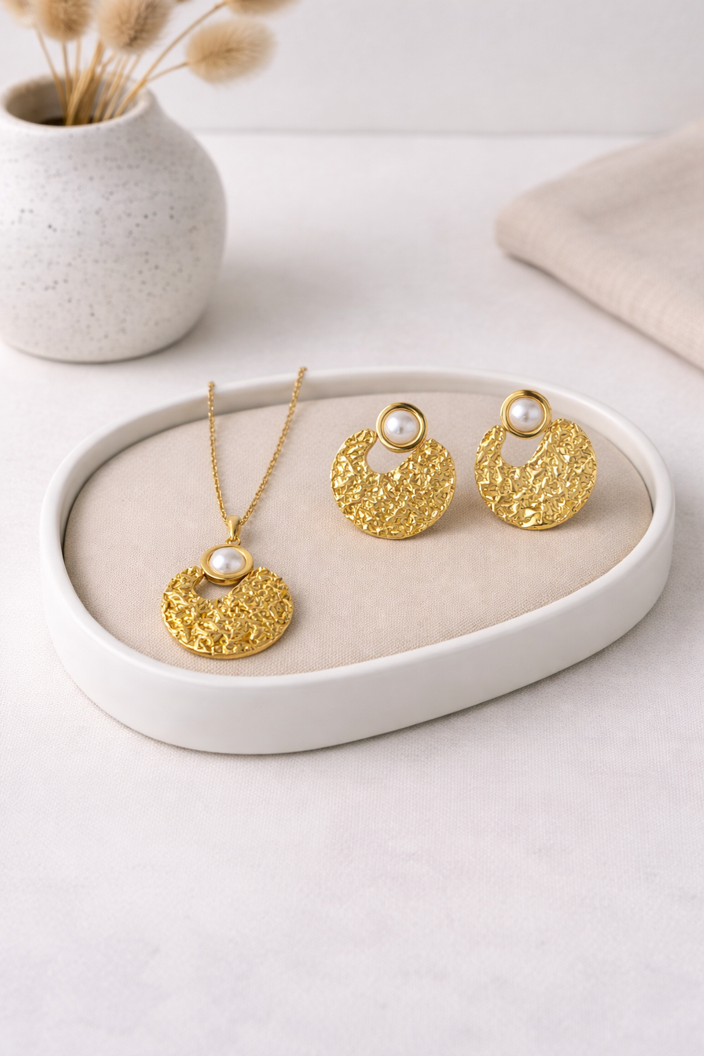Gold textured Aurelia Pearl Necklace and Earrings Set with white pearls, displayed on a beige tray.