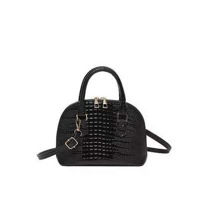 Black dome crossbody bag with a crocodile pattern texture.