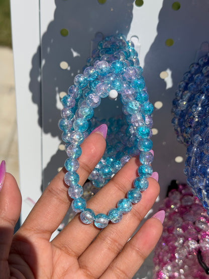 Blue Beaded Bracelets with multiple strands of sparkling, translucent blue and purple cracked glass beads, held in a hand.