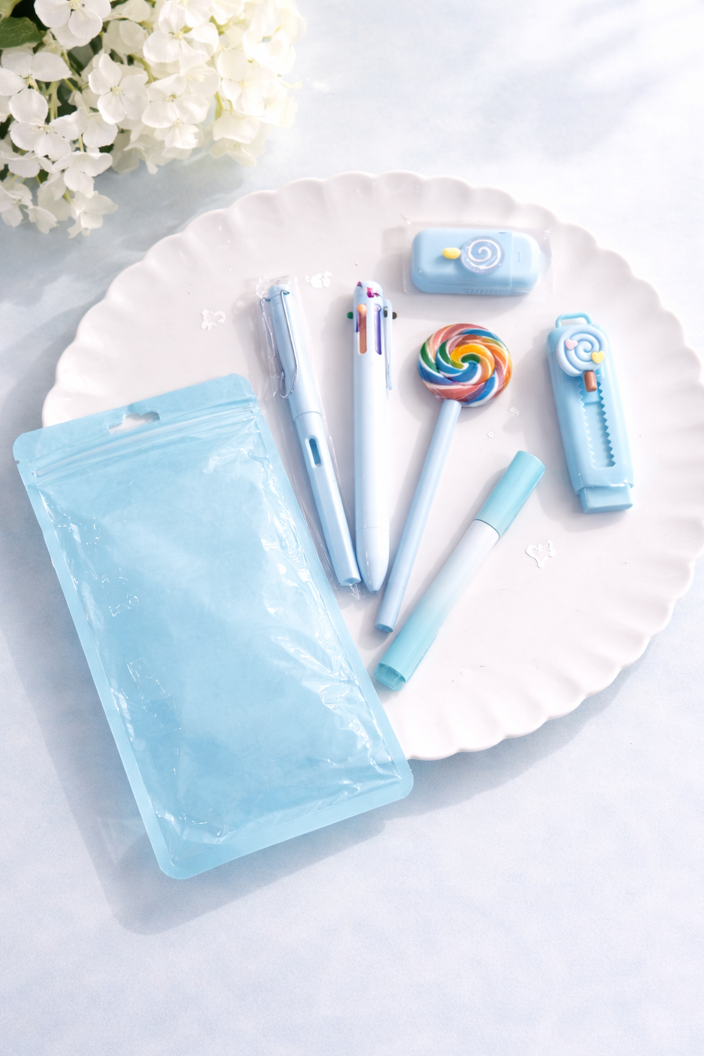 Light blue Sweet Desk Set with pens, marker, correction tape, and knife featuring lollipop designs, on a white plate.