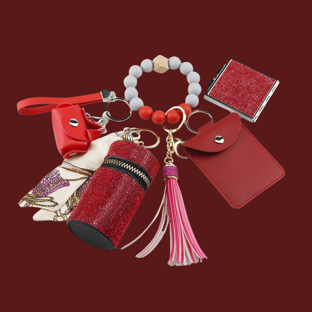 Red Luxe keychain wristlet accessory set featuring a beaded wristlet, rhinestone zip pouch, mini pouch, tassel charm, card holder, and sparkly compact mirror in coordinating colors.