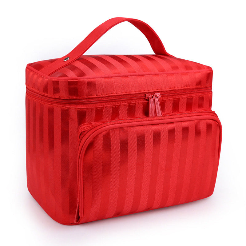 Red striped makeup bag by Bella with a top handle and front zip pocket, angled view.
