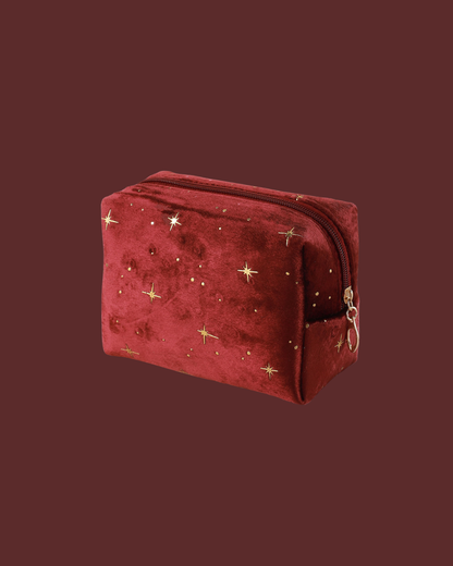 Red velvet pouch decorated with gold stars and small gold dots, featuring a gold zipper.