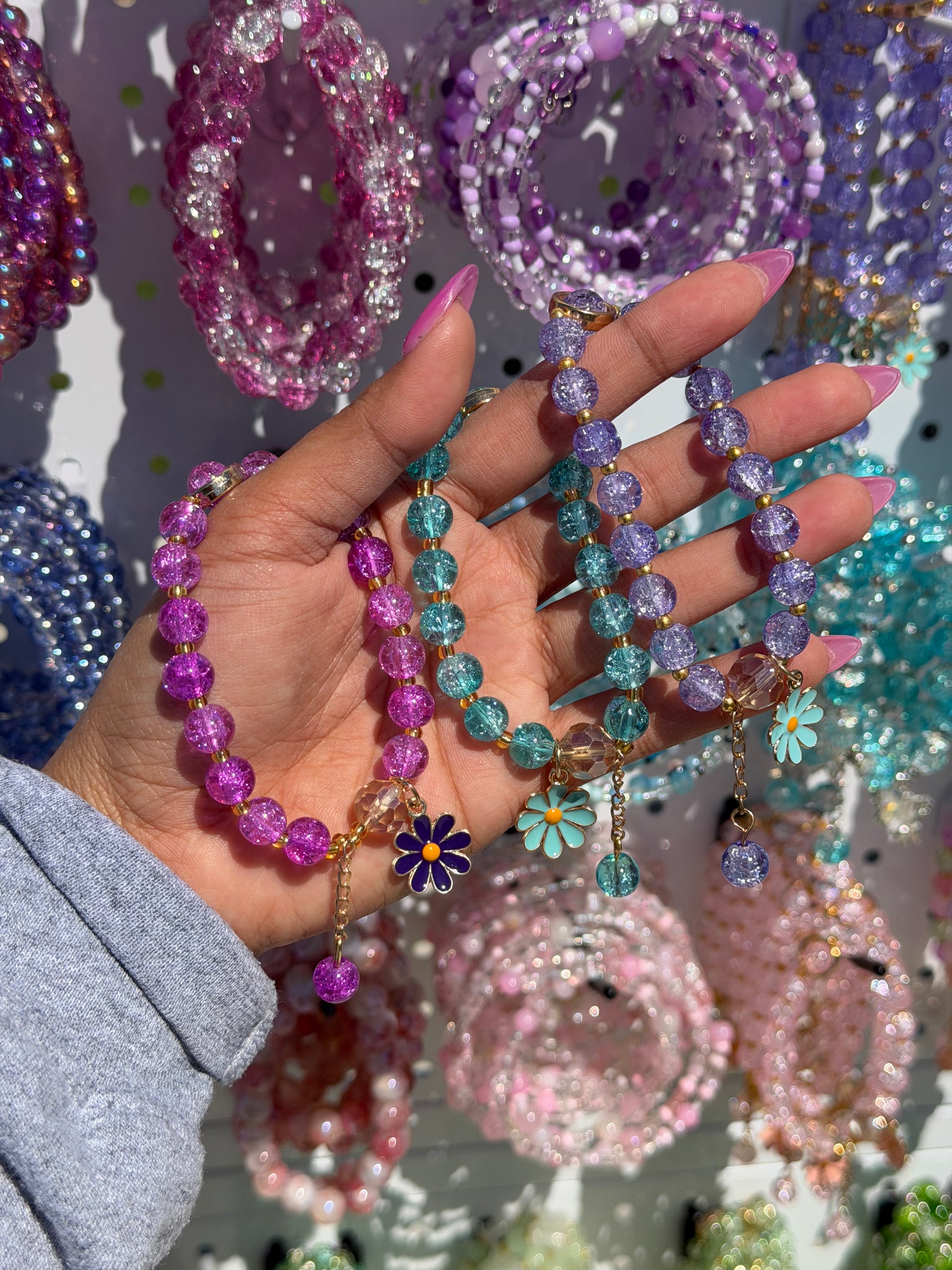 Daisy beaded bracelets in purple, blue, and magenta with cracked beads, gold spacers, and enamel daisy charms.