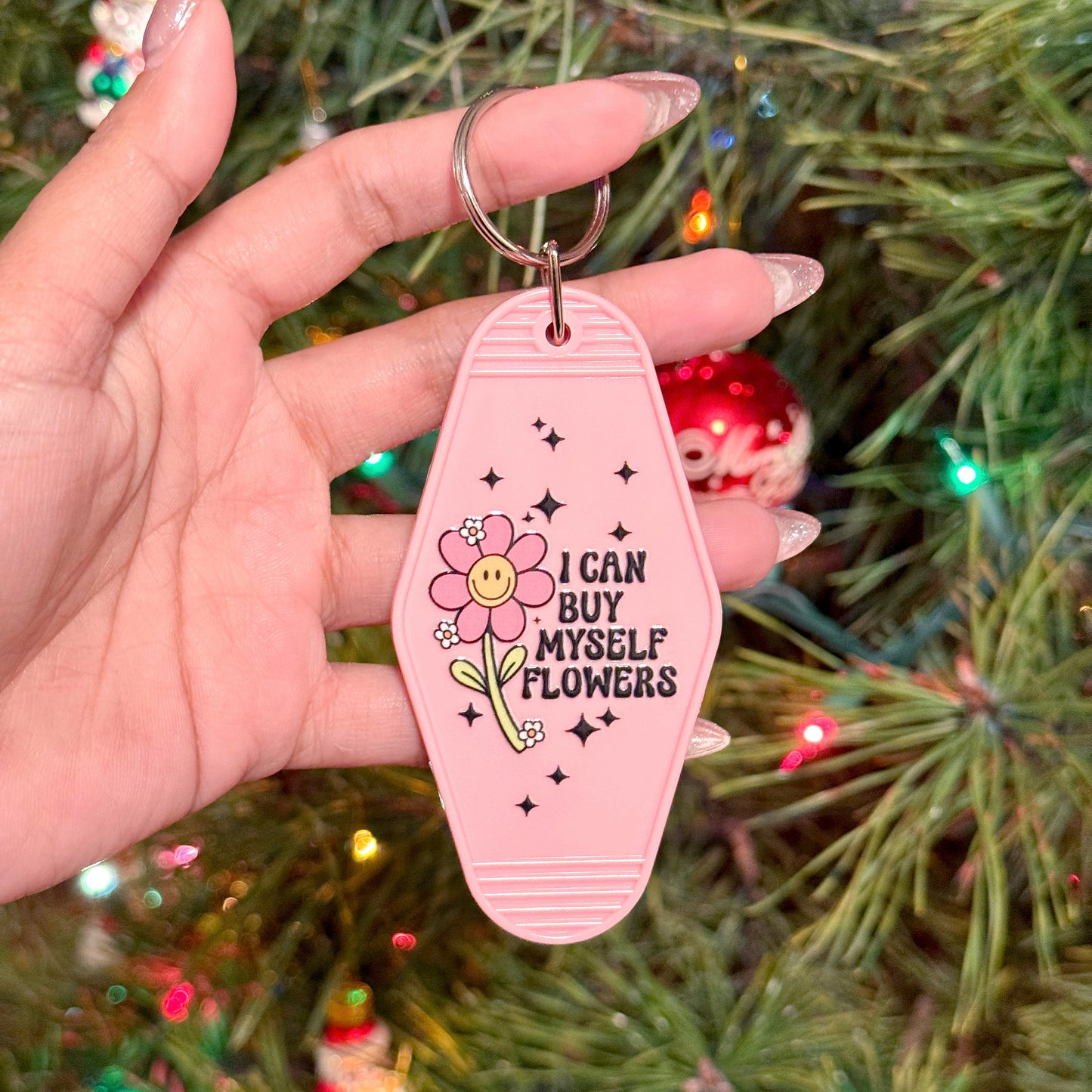 Pink motel keychain by an unknown brand featuring a flower graphic and a motivational phrase.