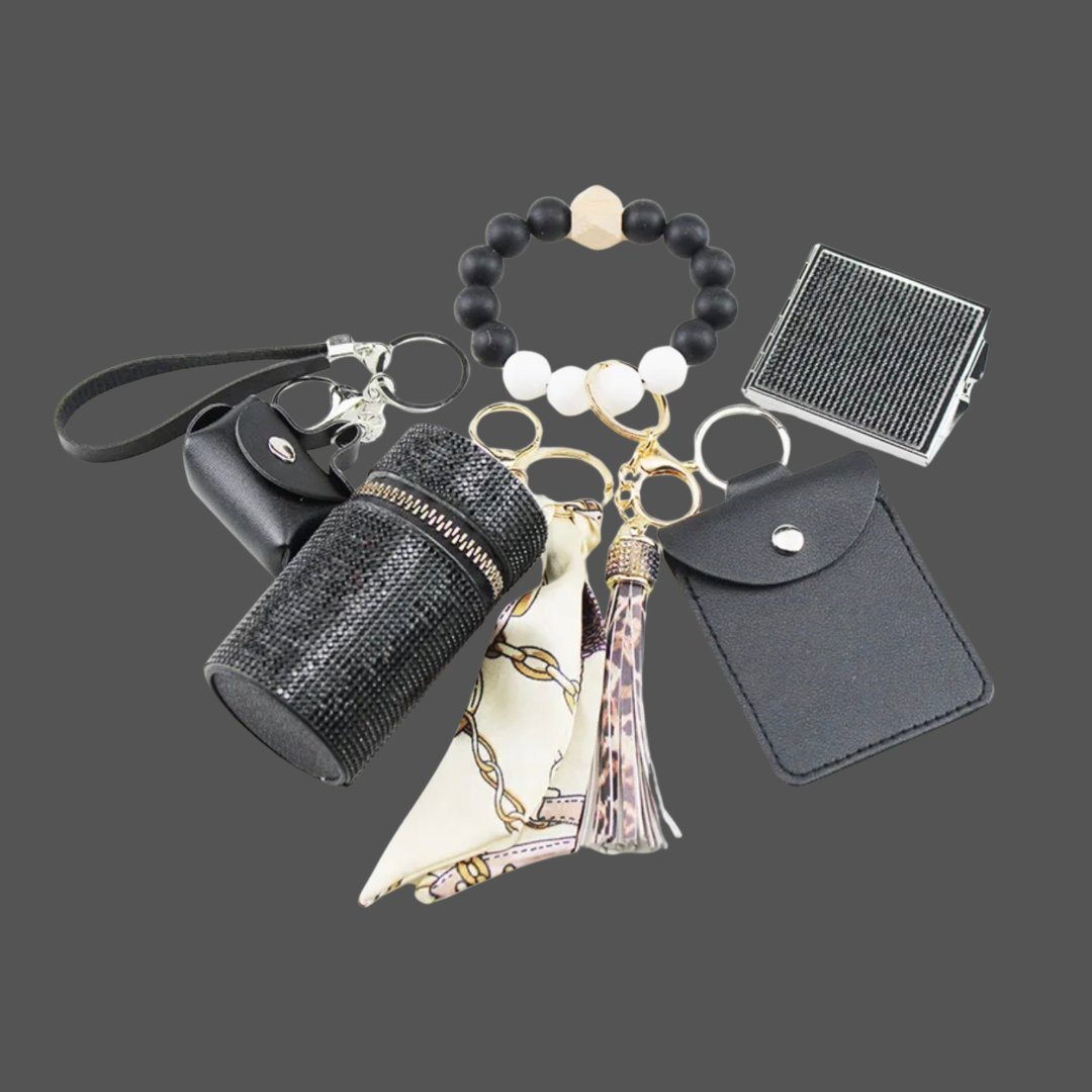 Black Luxe keychain wristlet accessory set featuring a beaded wristlet, rhinestone zip pouch, mini pouch, tassel charm, card holder, and sparkly compact mirror in coordinating colors.