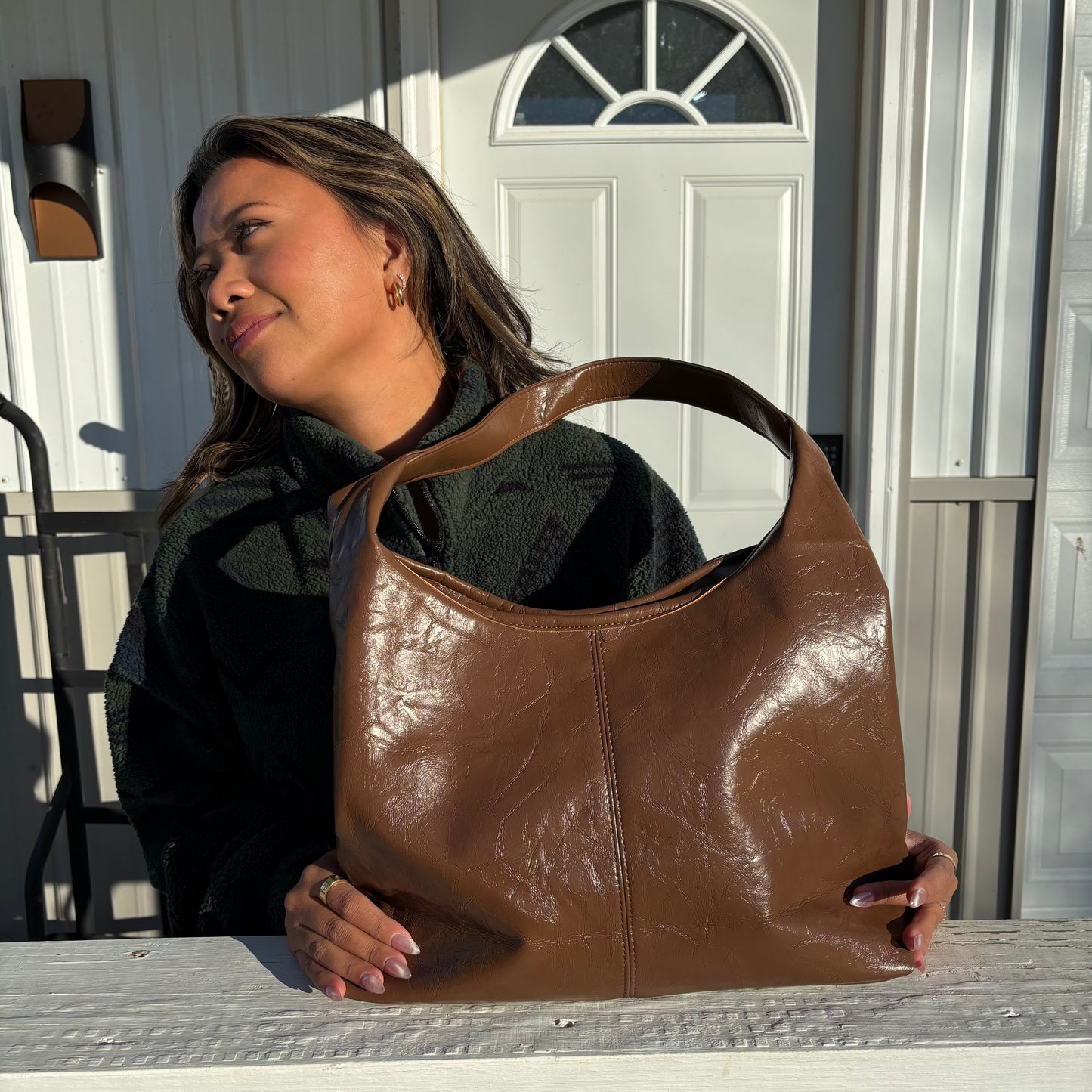 Brown leather tote bag by unknown vendor, in front of a woman wearing a fuzzy green jacket.