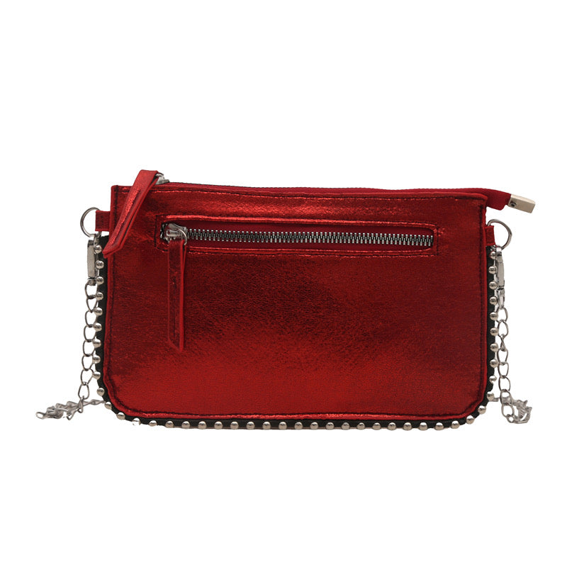Red metallic mini bag with chain strap by Sweetheart, featuring silver studded trim and a zippered pocket.