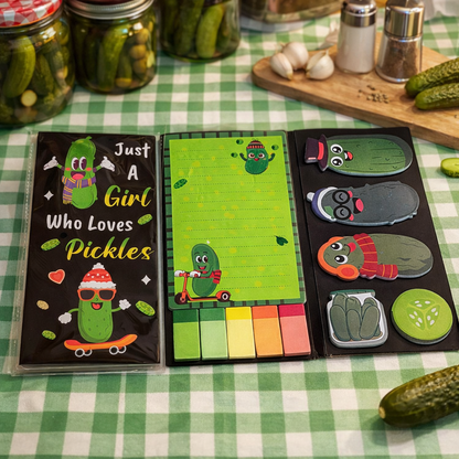 Foldable sticky notepads with pickle designs, with multiple styles available, on a green and white checkered surface.
