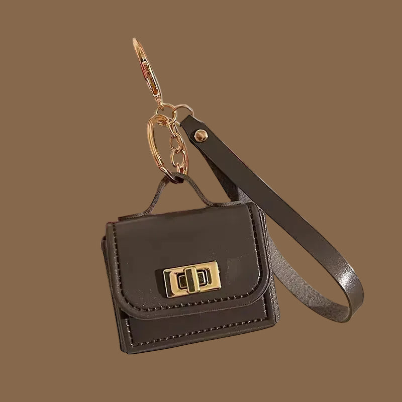 Mini leather purse bag charm with gold hardware and wrist strap.