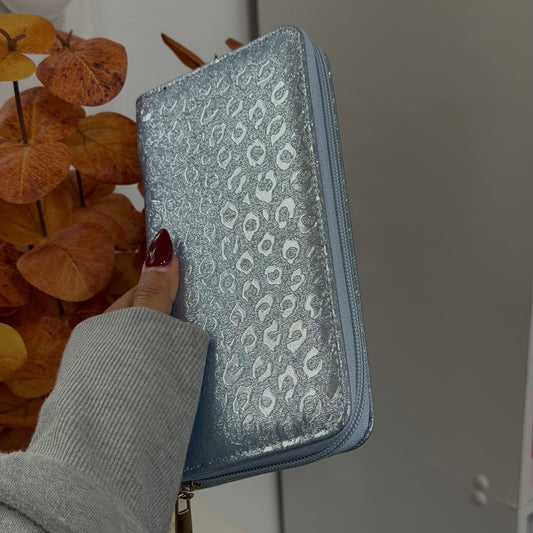 Hand holding a glittery leopard patterned Wallet with blurred background