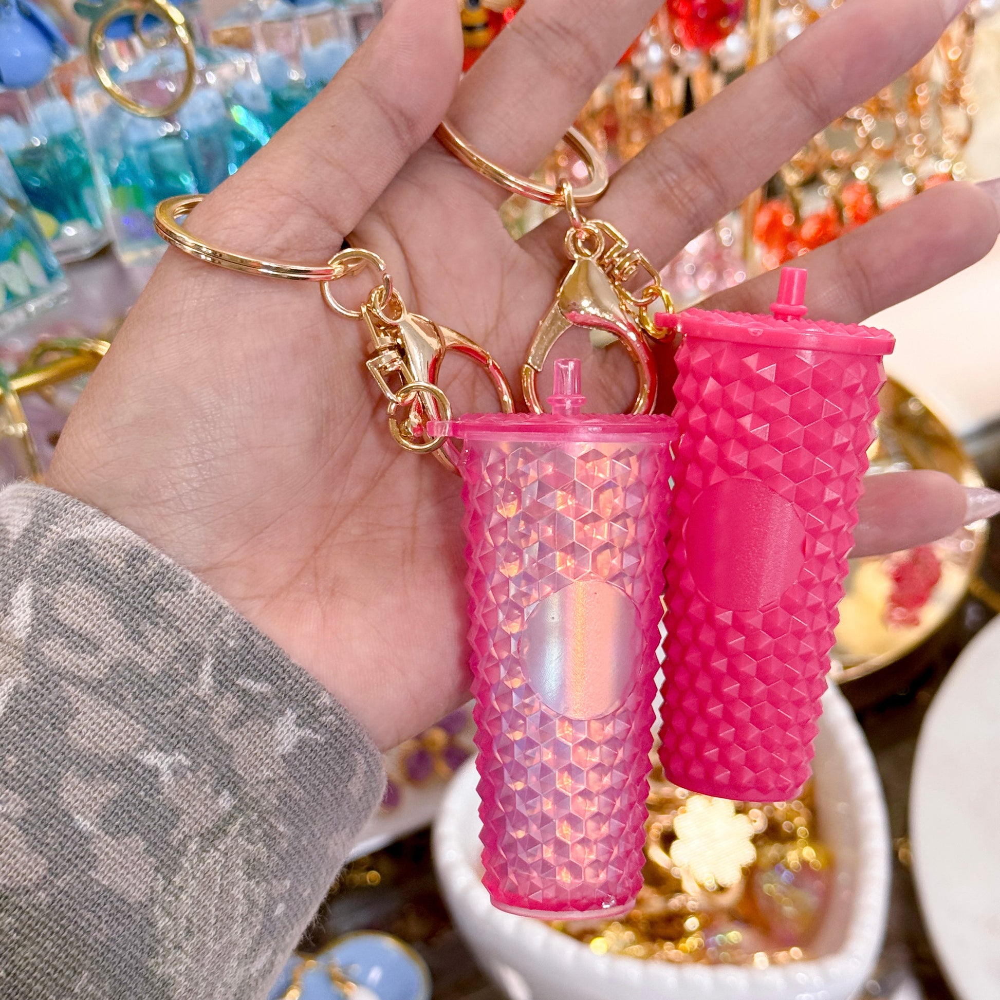 Pink drink bag charms from Valentine's Day Collection, featuring textured, geometric patterns with gold keychains.
