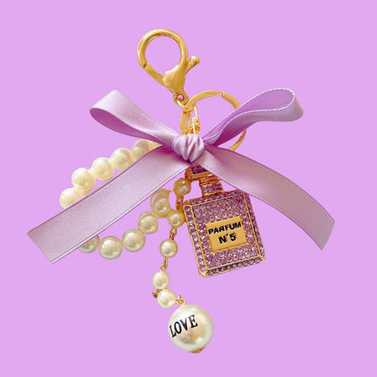 Crystal bag charm in a parfum shape with pearls by an unknown vendor, featuring a lavender bow and "LOVE" detail.
