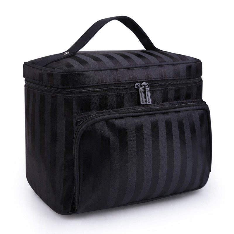 Black makeup bag by Bella with subtle vertical stripes, a top handle, and two zippered compartments.