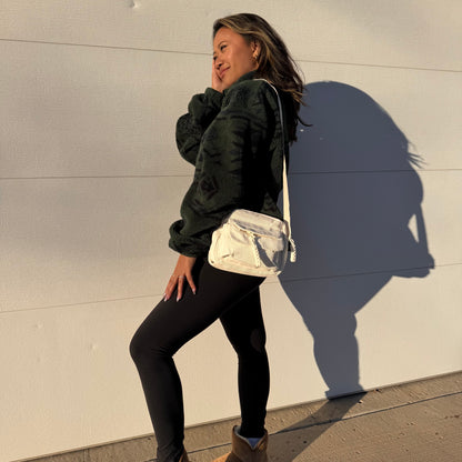Beige corduroy crossbody bag by Baggu, with adjustable strap, worn with a fleece top and leggings.