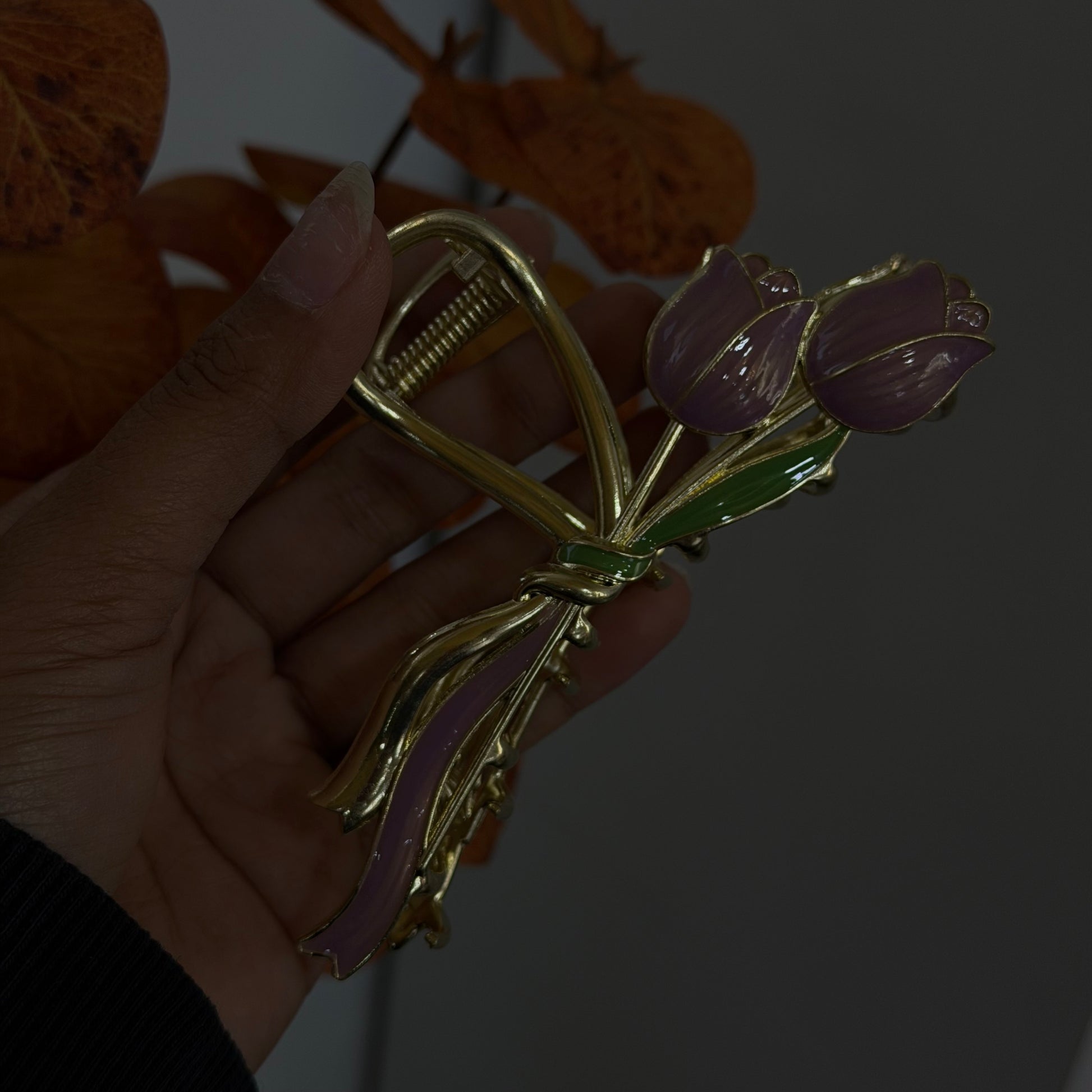 Gold bow-shaped hair claw with purple tulip flowers and green enamel leaves, featuring a smooth glossy finish.