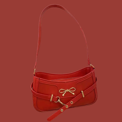 Small red shoulder handbag with bow detail, adjustable strap, and gold-tone hardware, displayed on a red background.